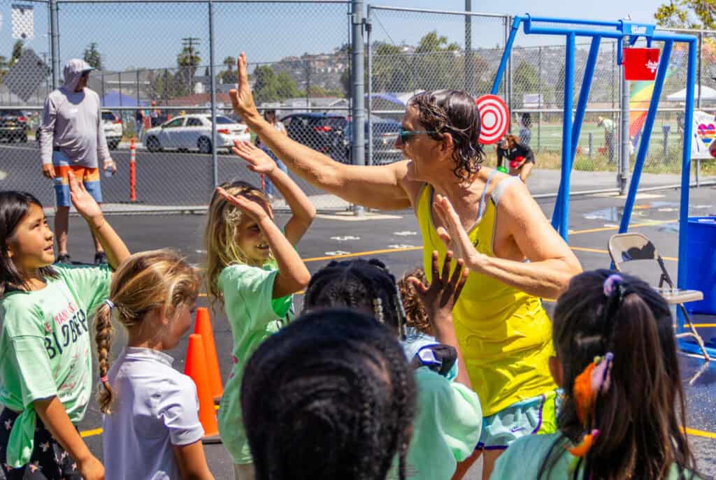 A teacher gives her students high-fives after she participates in the Jog-a-thon soak zone.