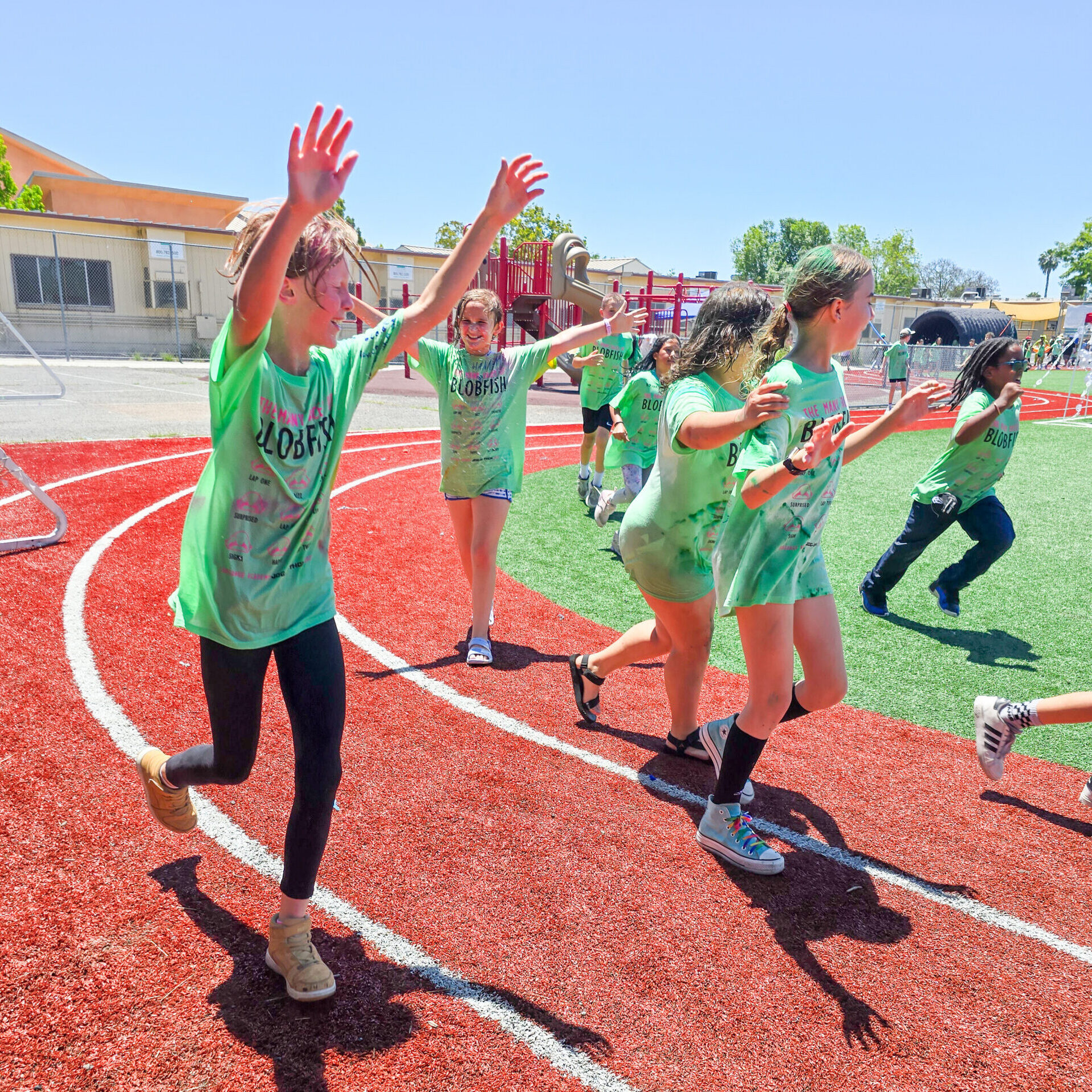 Students run along the track with their arms up in the air during jog-a-thon.