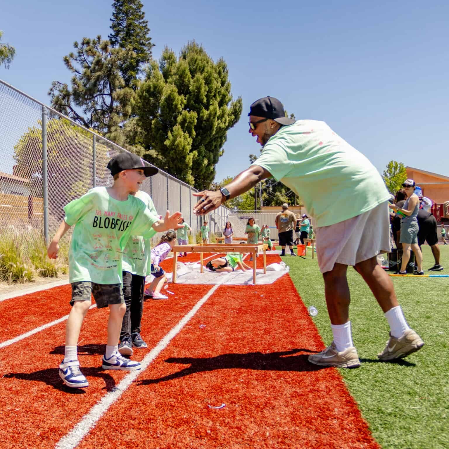 A boy and a parent volunteer high five along the Jog-a-thon course.