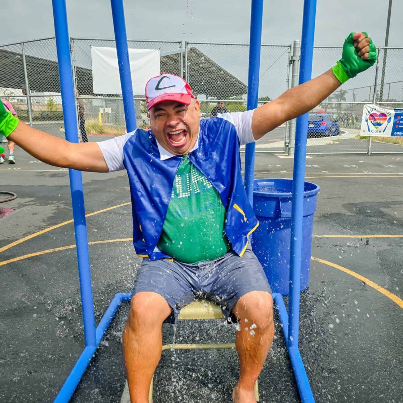 A teacher wearing a pokemon costume is soaked by a bucket of water at a splash tower.